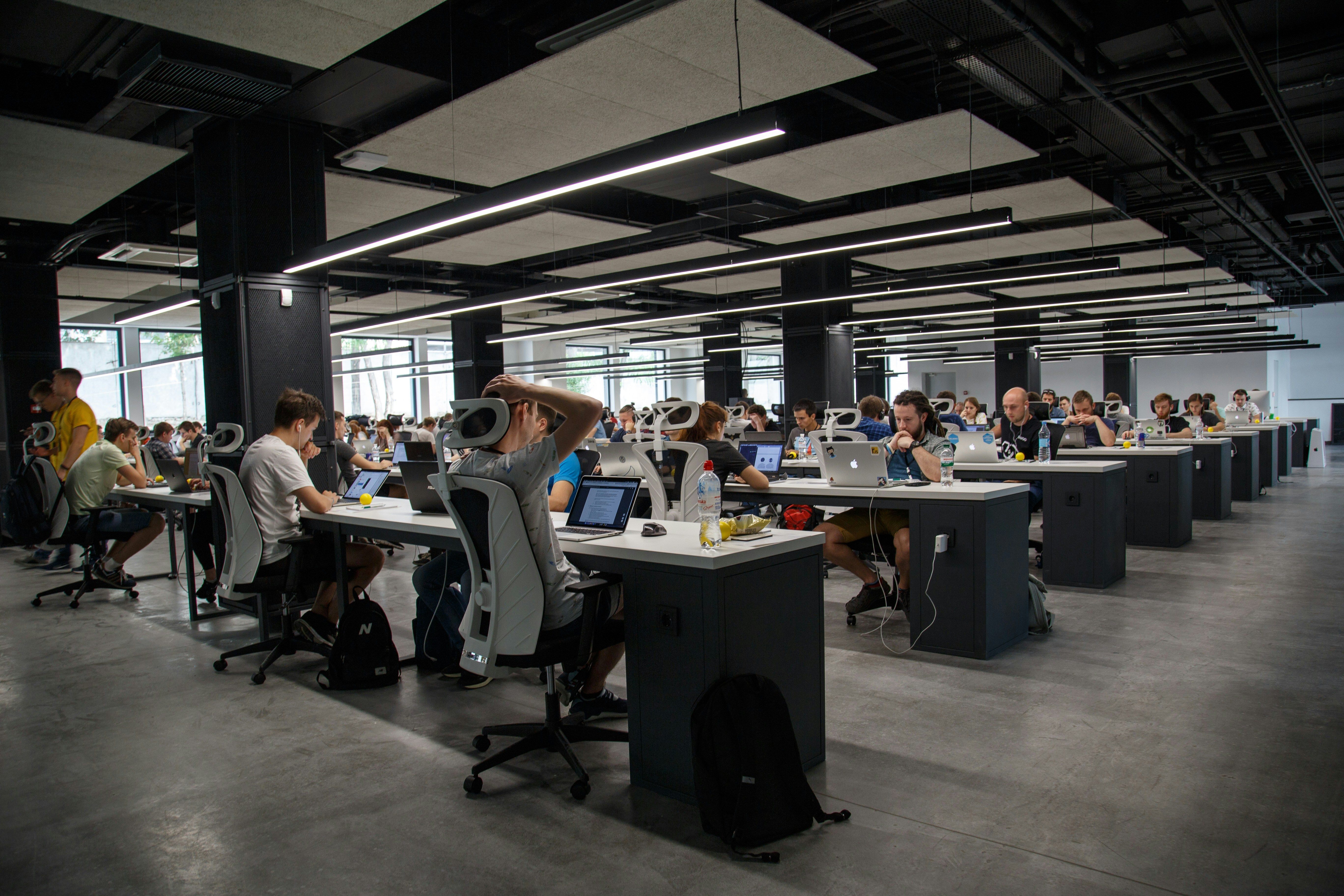 Modern open-plan sales office with exposed brick, ductwork, and rows of workstations